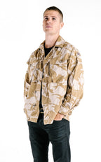 A model displaying the British Desert DPM pattern combat shirt, worn open over a black t-shirt for a tactical style.