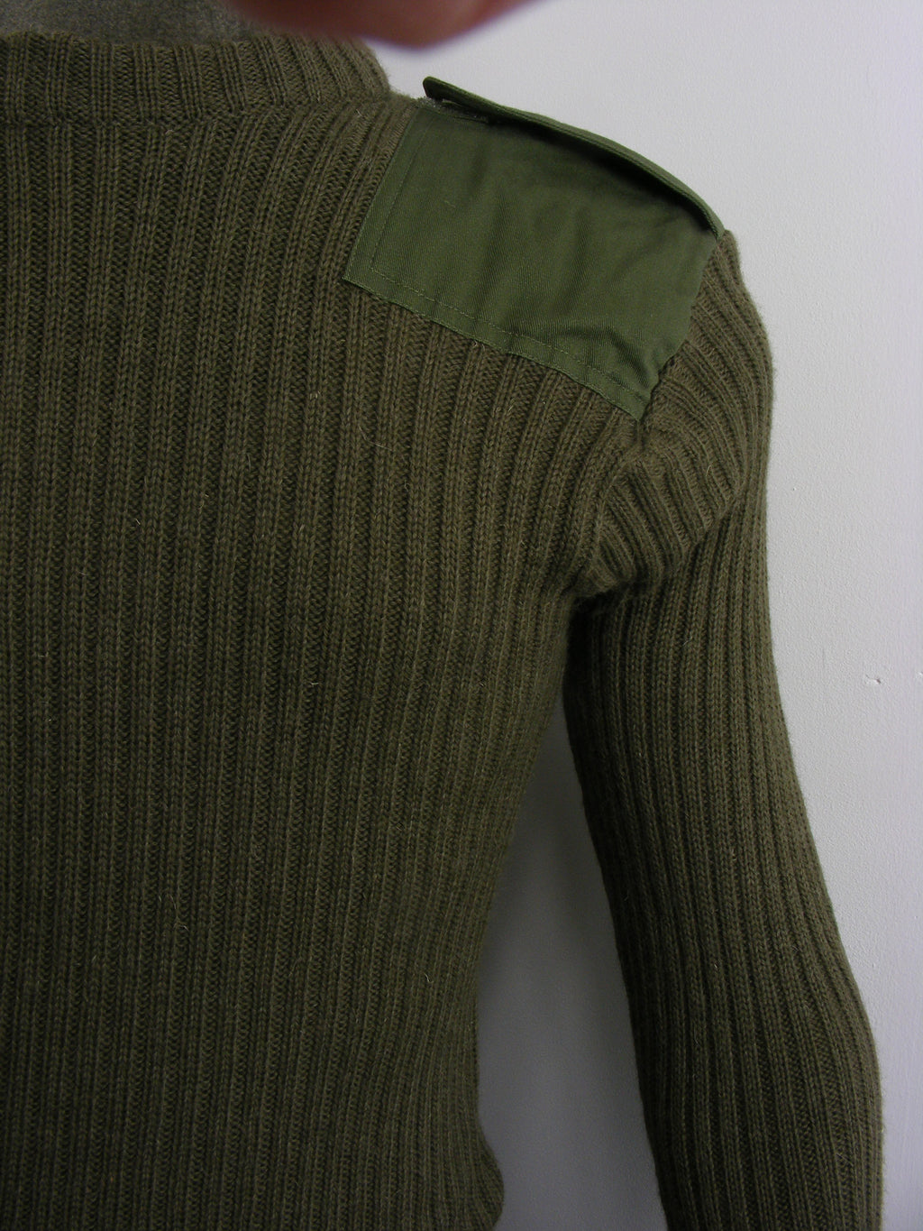 Close-up of the shoulder detail on a genuine British Army ribbed wool jumper, highlighting the durable military polycotton epaulette and stitch work.