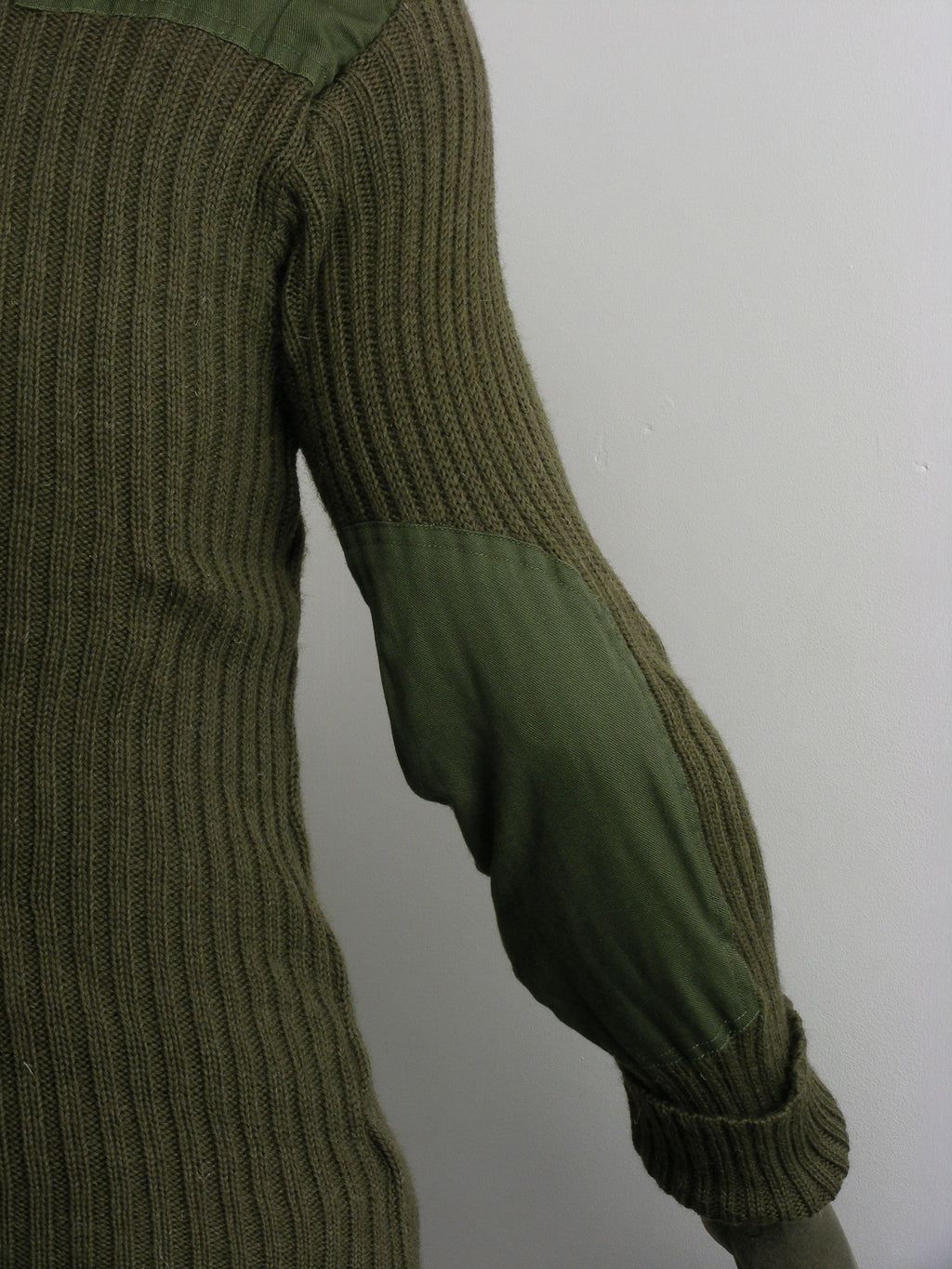 Detailed side view of the olive green military woolly pully, focusing on the reinforced polycotton elbow patch designed for field durability.