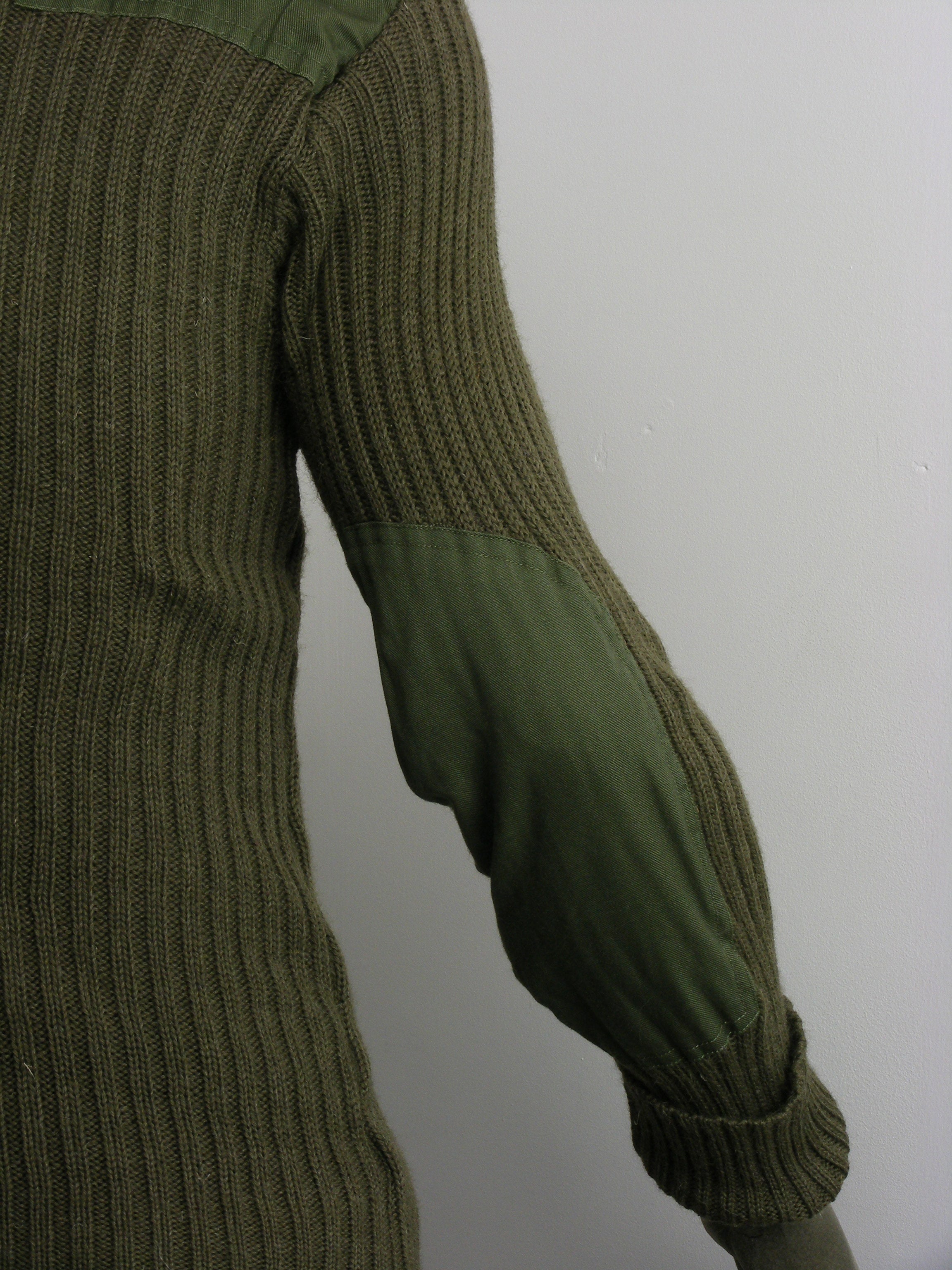 Detailed side view of the olive green military woolly pully, focusing on the reinforced polycotton elbow patch designed for field durability.