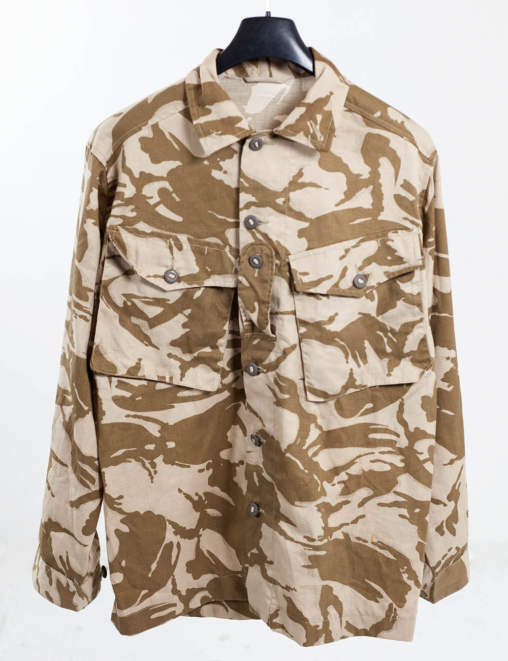 Front studio shot of the British desert combat shirt hung on a hanger to show the full tactical field design.