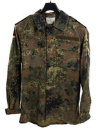 Genuine German Army Flecktarn shirt on hanger, displaying official Bundeswehr internal manufacturing labels, shoulder epaulettes, and flag patches.