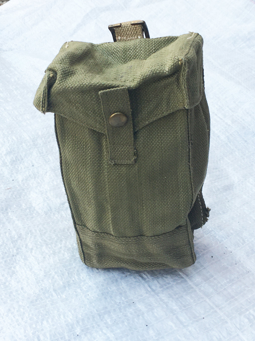 Three-quarter view of a green British Army Mark III ammo pouch from the second world war era with brass fittings.