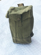 Three-quarter view of a green British Army Mark III ammo pouch from the second world war era with brass fittings.
