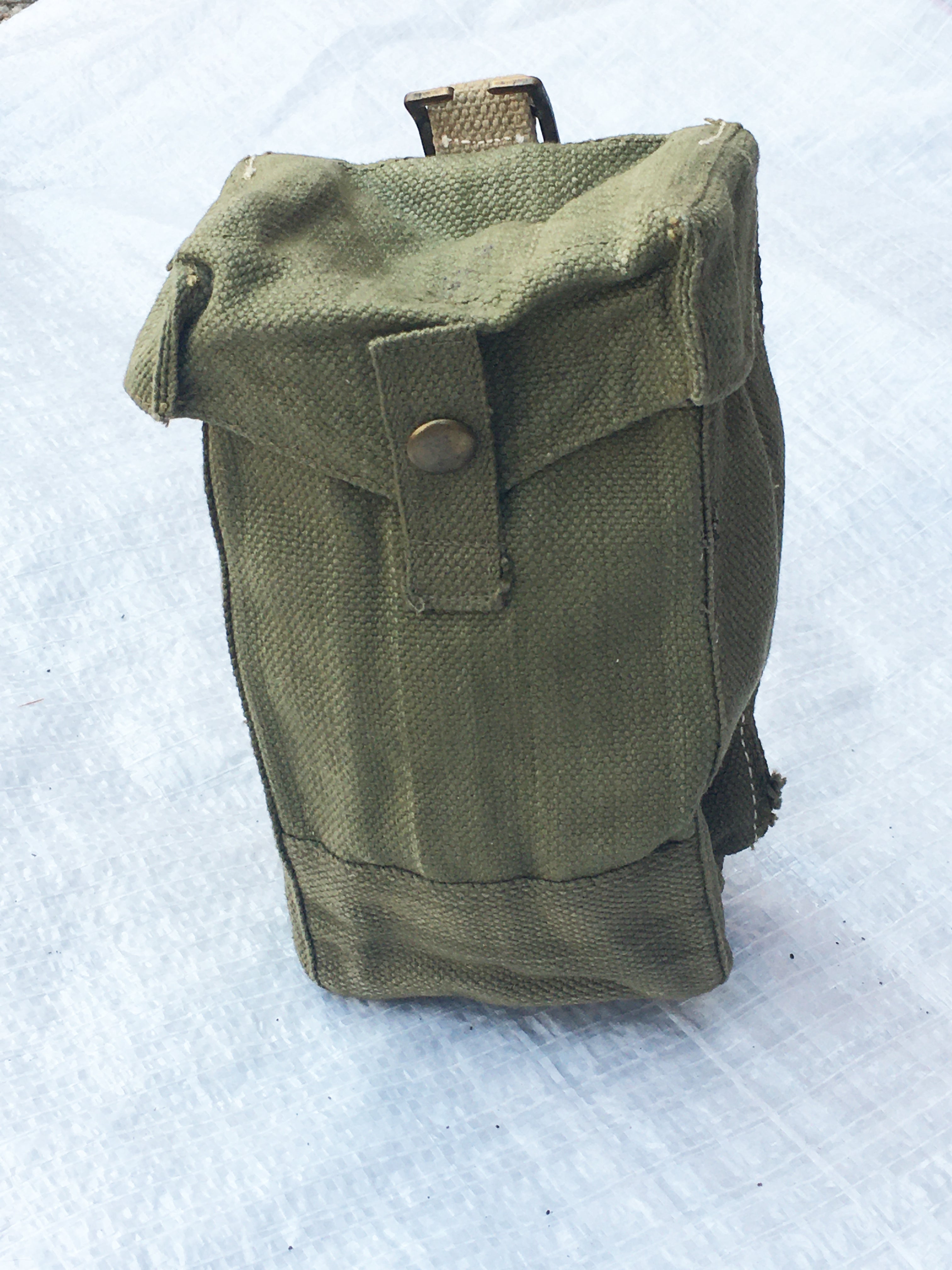 Three-quarter view of a green British Army Mark III ammo pouch from the second world war era with brass fittings.