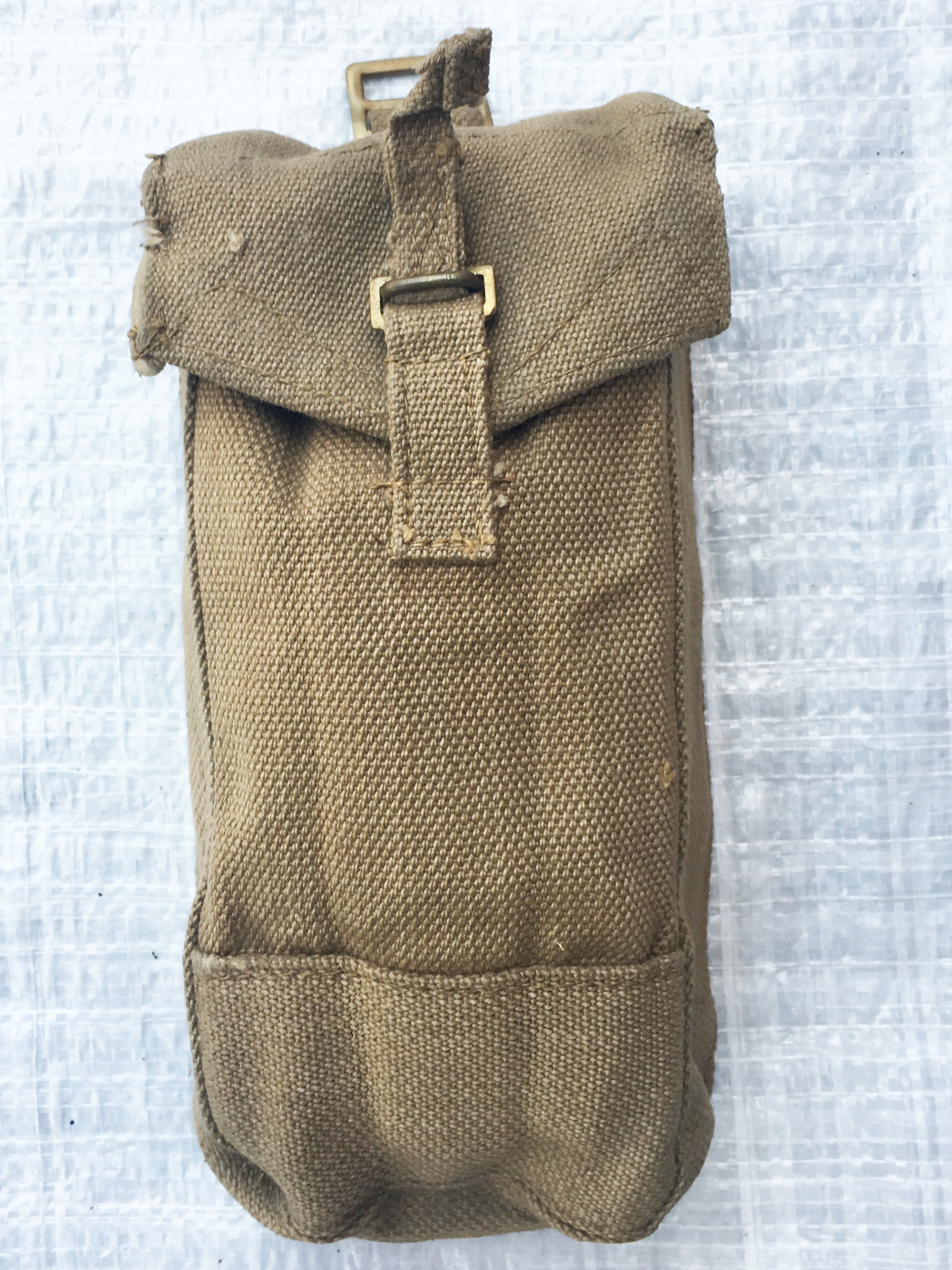 Front view of a durable WW2 era British Army Mark III canvas ammo pouch showing brass hardware and rugged texture.