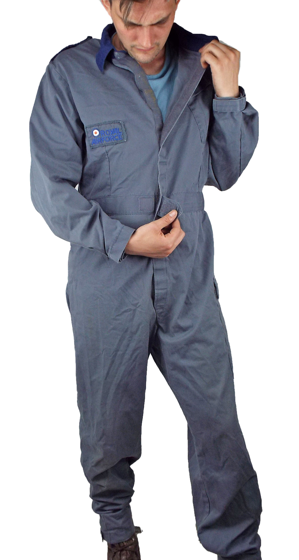 Close-up of a person adjusting the hook-and-loop front closure on a vintage British RAF jumpsuit with an embroidered chest patch.